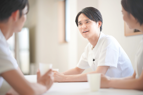 デスクで談笑・相談をする若手の医療スタッフたち