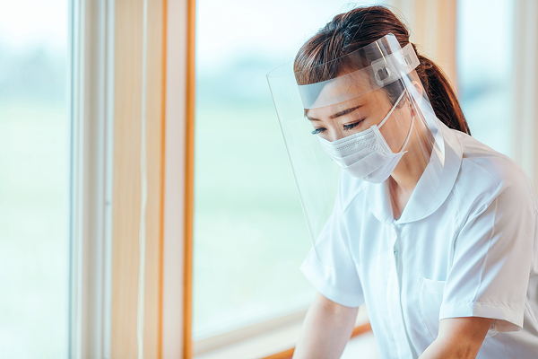 フェイスシールドとマスクを着用して処置を行う女性スタッフ