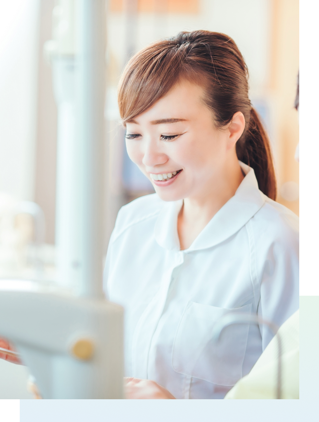 歯科医院の診察室で、患者に向かって優しく微笑む女性スタッフ